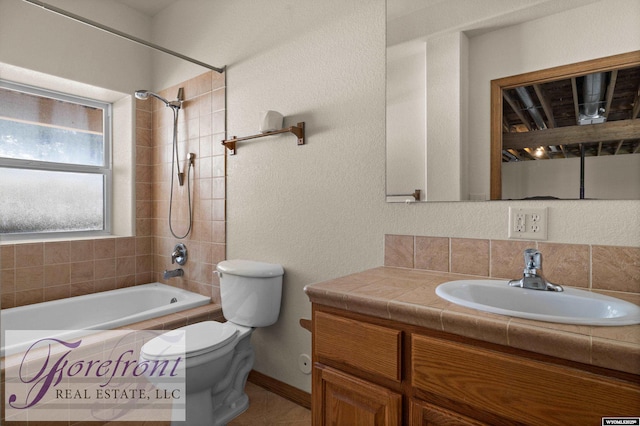 full bath with tiled shower / bath, toilet, vanity, and a textured wall