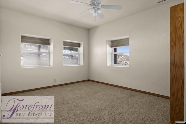 empty room with a wealth of natural light, carpet flooring, baseboards, and ceiling fan