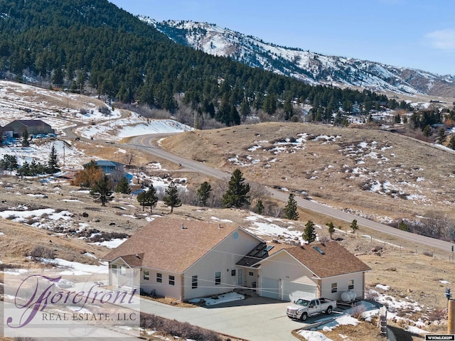 snowy aerial view featuring a mountain view and a view of trees