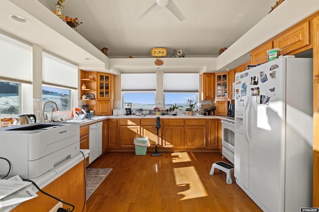 kitchen featuring white appliances, brown cabinetry, light wood-style flooring, light countertops, and glass insert cabinets