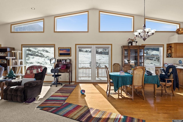 dining space featuring high vaulted ceiling, an inviting chandelier, and wood finished floors