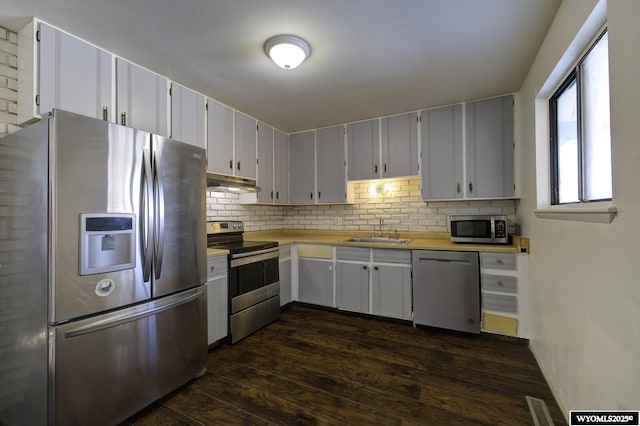 kitchen with sink, dark wood-type flooring, white cabinetry, stainless steel appliances, and tasteful backsplash