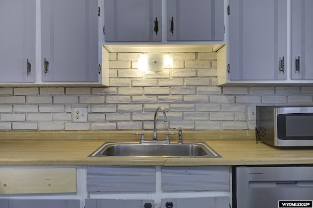 kitchen with tasteful backsplash, appliances with stainless steel finishes, and sink