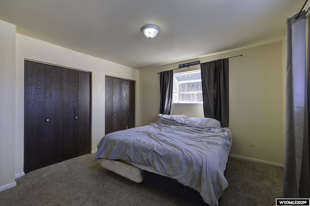 bedroom with multiple closets and dark carpet