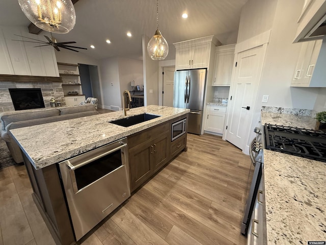 kitchen featuring sink, appliances with stainless steel finishes, white cabinetry, a kitchen island with sink, and dark brown cabinets