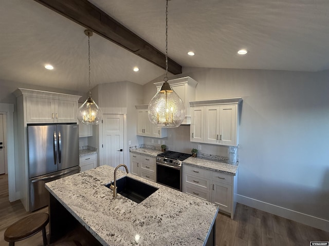 kitchen featuring appliances with stainless steel finishes, an island with sink, sink, white cabinets, and hanging light fixtures