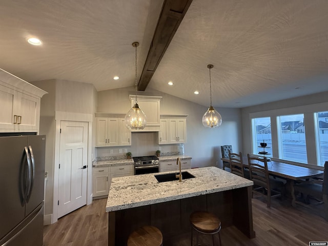 kitchen with appliances with stainless steel finishes, pendant lighting, sink, white cabinets, and a center island with sink