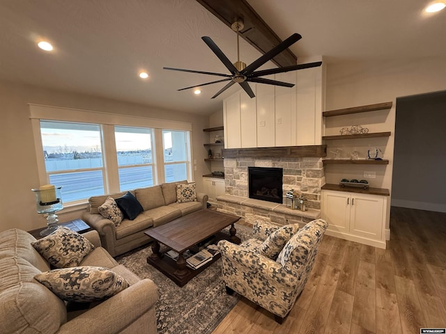 living room featuring hardwood / wood-style flooring, ceiling fan, a fireplace, and vaulted ceiling with beams