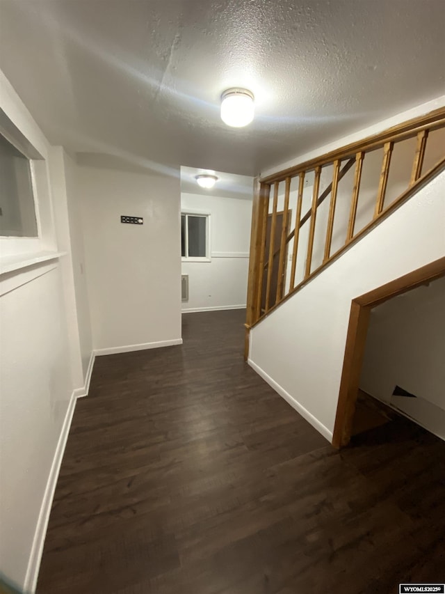 hallway with dark hardwood / wood-style floors and a textured ceiling