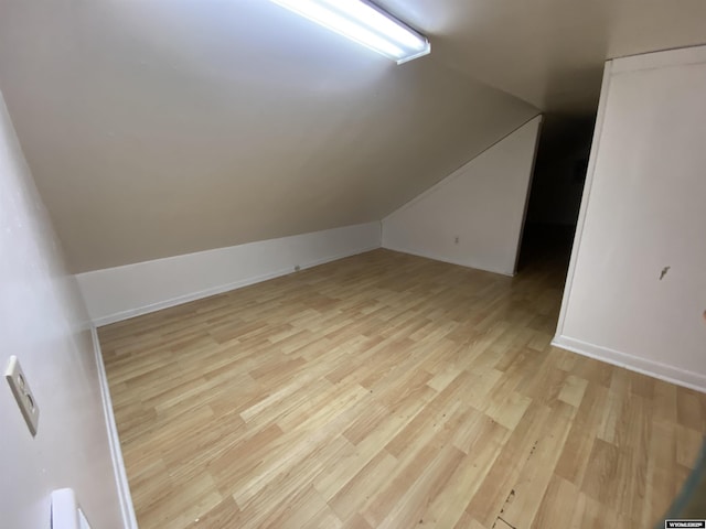 bonus room with vaulted ceiling and light wood-type flooring