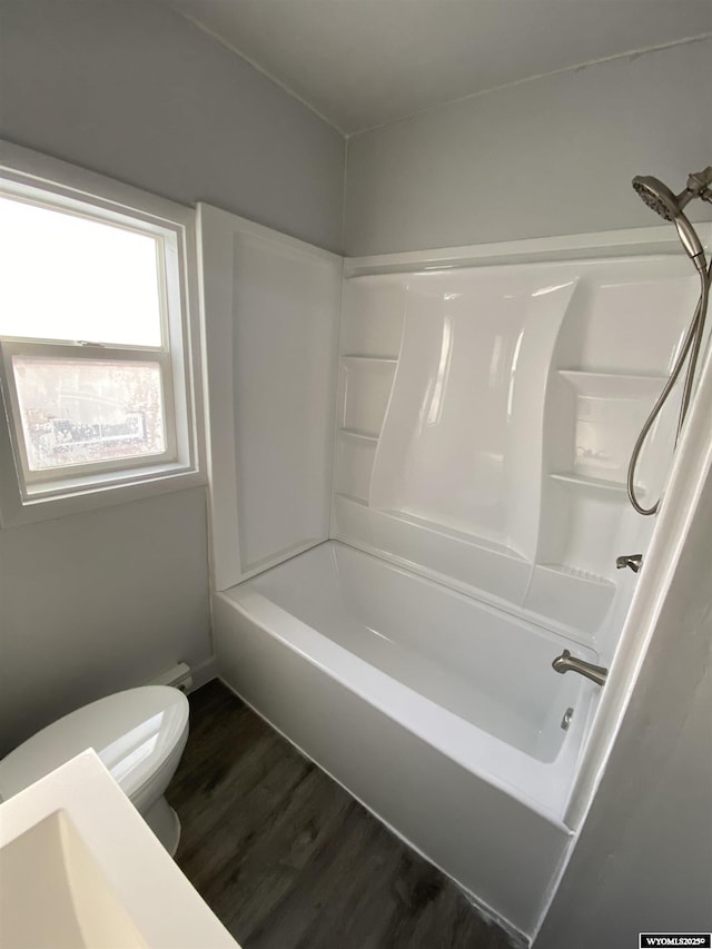 bathroom with hardwood / wood-style floors, shower / bathtub combination, and toilet