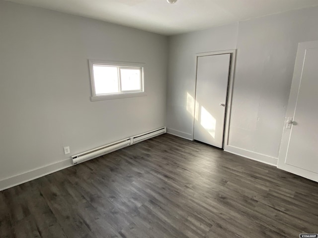 unfurnished bedroom featuring dark wood-type flooring and a baseboard heating unit