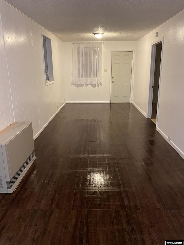 hallway featuring dark hardwood / wood-style flooring, heating unit, and a textured ceiling