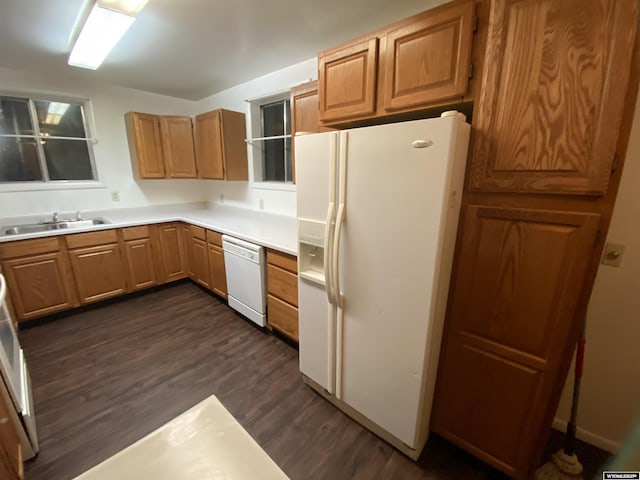 kitchen with dark wood-type flooring, white appliances, and sink