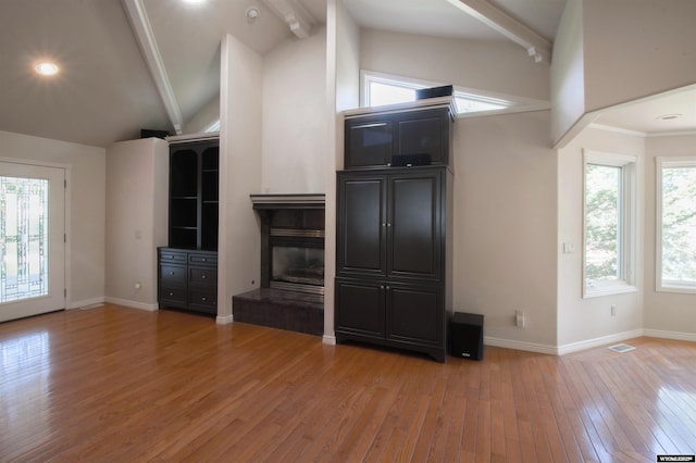 unfurnished living room with beamed ceiling, wood-type flooring, and high vaulted ceiling