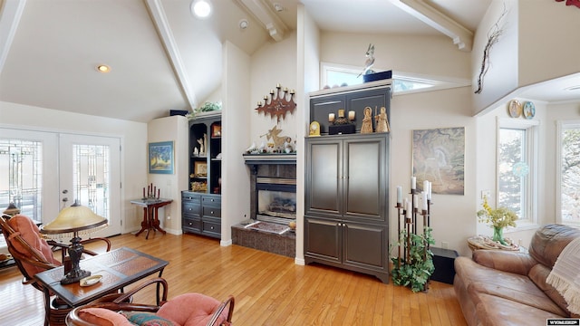 living room with high vaulted ceiling, beamed ceiling, a high end fireplace, light wood-type flooring, and french doors