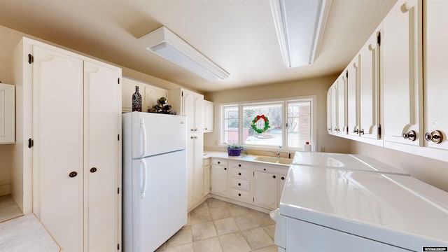 kitchen with white cabinetry, sink, and white fridge