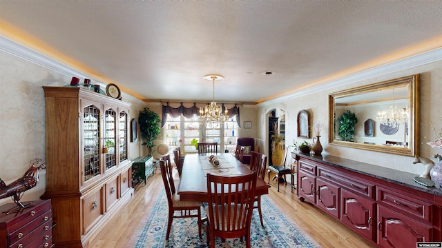 dining room with ornamental molding, a textured ceiling, a notable chandelier, and light wood-type flooring