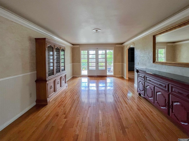 unfurnished living room with crown molding, light wood-type flooring, and french doors