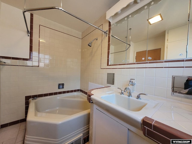 bathroom with tasteful backsplash, vanity, tiled shower / bath combo, and tile walls