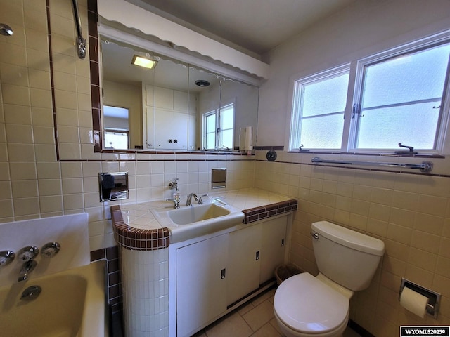 bathroom featuring tile walls, a tub to relax in, tile patterned flooring, vanity, and toilet