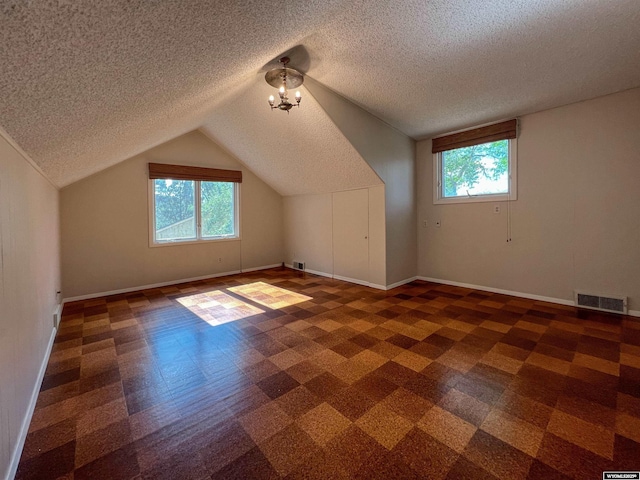 additional living space featuring lofted ceiling, a wealth of natural light, and a textured ceiling