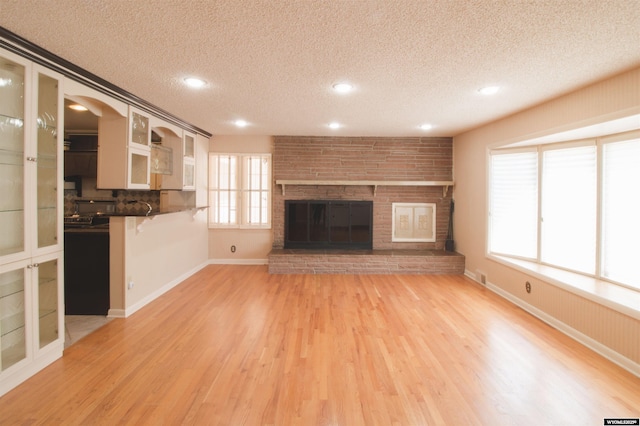 unfurnished living room featuring a textured ceiling, a fireplace, and light wood-type flooring