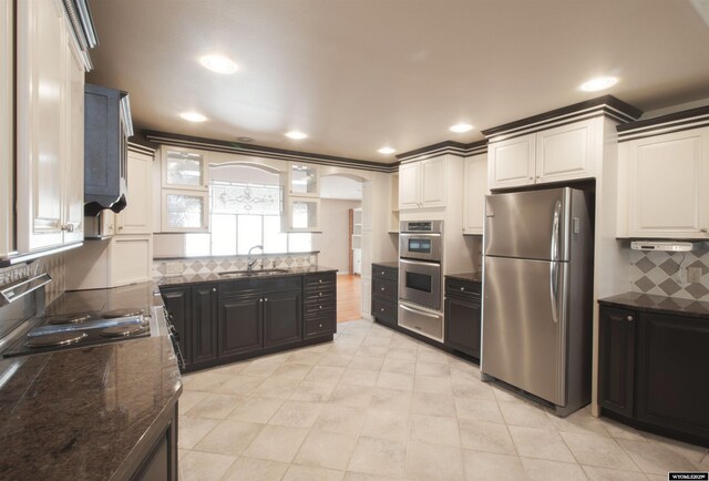 kitchen featuring tasteful backsplash, white cabinetry, appliances with stainless steel finishes, and sink