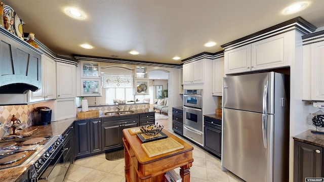 kitchen with white cabinetry, light tile patterned floors, dark stone counters, stainless steel appliances, and backsplash