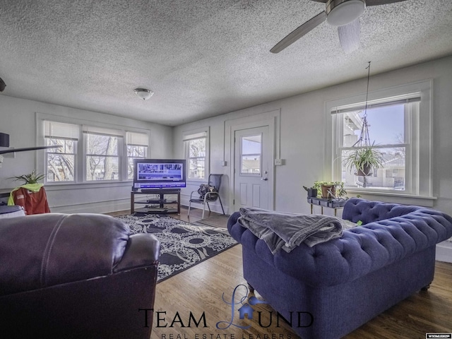 living room featuring ceiling fan, wood-type flooring, and a textured ceiling