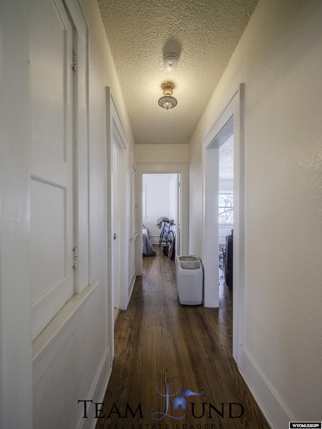 hall with dark hardwood / wood-style flooring and a textured ceiling