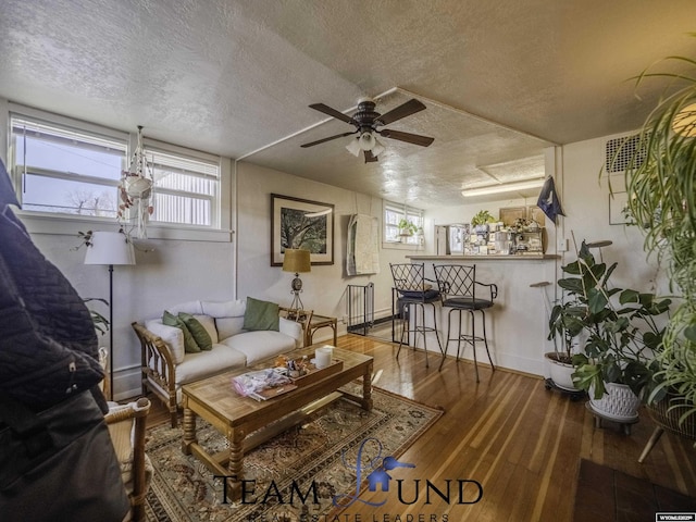 living room featuring ceiling fan, hardwood / wood-style flooring, and a textured ceiling