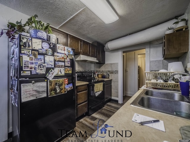 kitchen with dark brown cabinetry, sink, a textured ceiling, dark hardwood / wood-style flooring, and black appliances