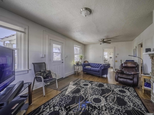 living room with a textured ceiling, dark wood-type flooring, and ceiling fan