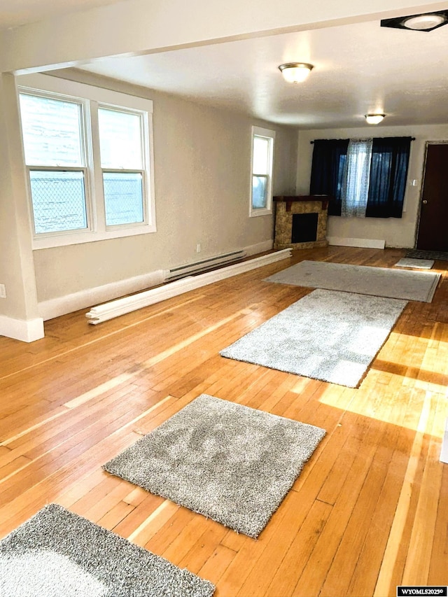 unfurnished living room with hardwood / wood-style floors, a fireplace, and baseboards