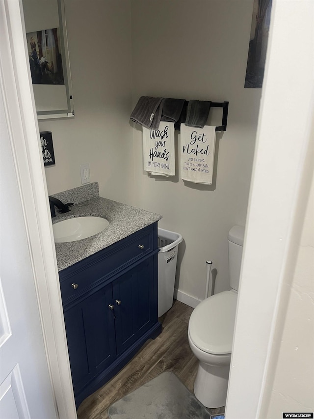 bathroom with baseboards, vanity, toilet, and wood finished floors