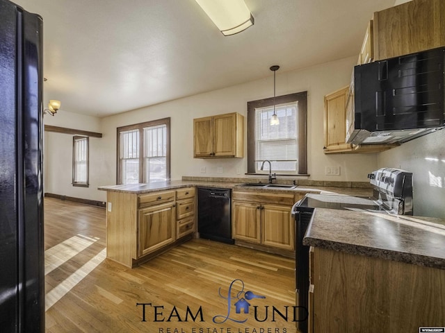 kitchen featuring sink, light wood-type flooring, kitchen peninsula, pendant lighting, and black appliances