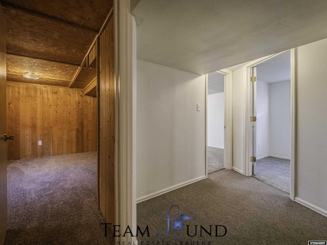 hallway with carpet floors and wood walls