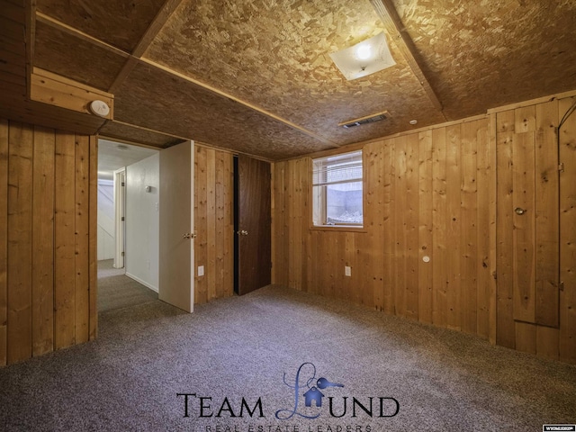 unfurnished room with carpet floors and wood walls