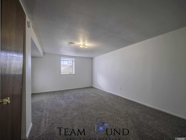 empty room with dark carpet and a textured ceiling