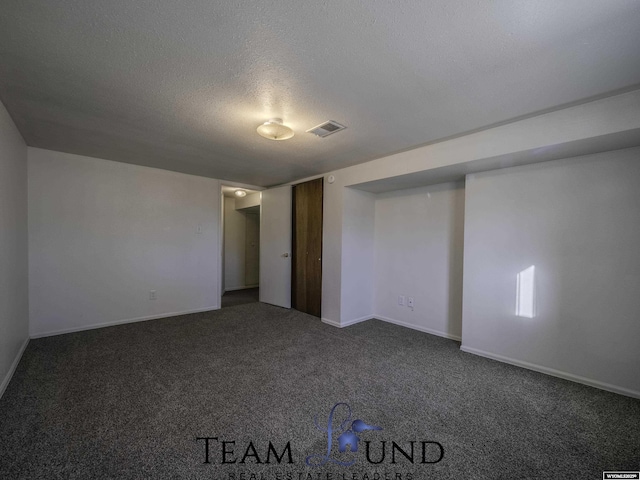 unfurnished bedroom with dark carpet and a textured ceiling