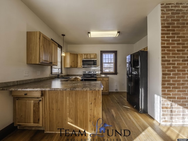 kitchen featuring sink, hanging light fixtures, range with electric cooktop, black fridge, and kitchen peninsula