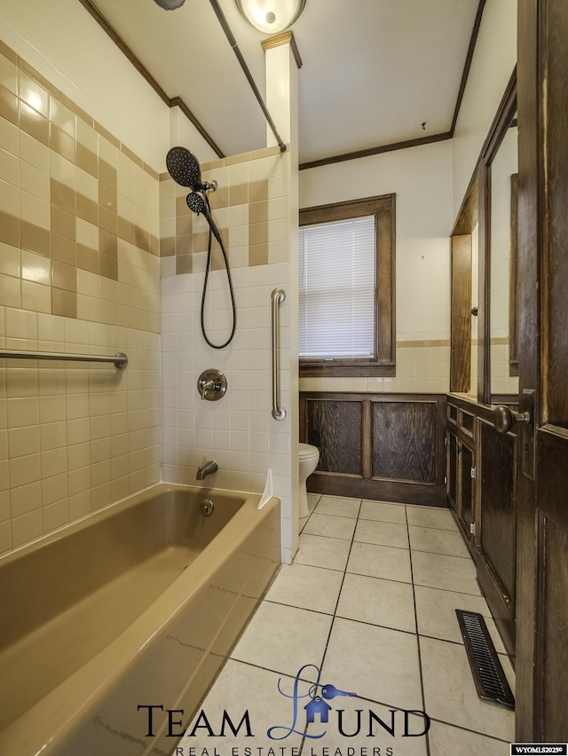 bathroom featuring tile walls, tile patterned flooring, ornamental molding, tiled shower / bath combo, and toilet