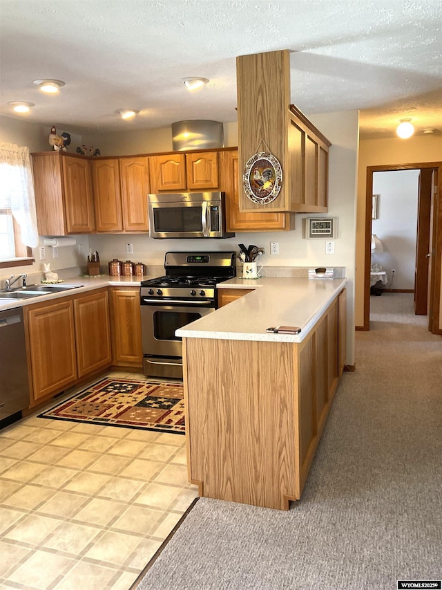 kitchen with stainless steel appliances, kitchen peninsula, sink, and a textured ceiling