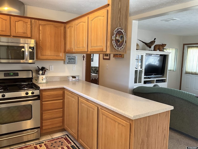 kitchen featuring stainless steel appliances, kitchen peninsula, and a textured ceiling