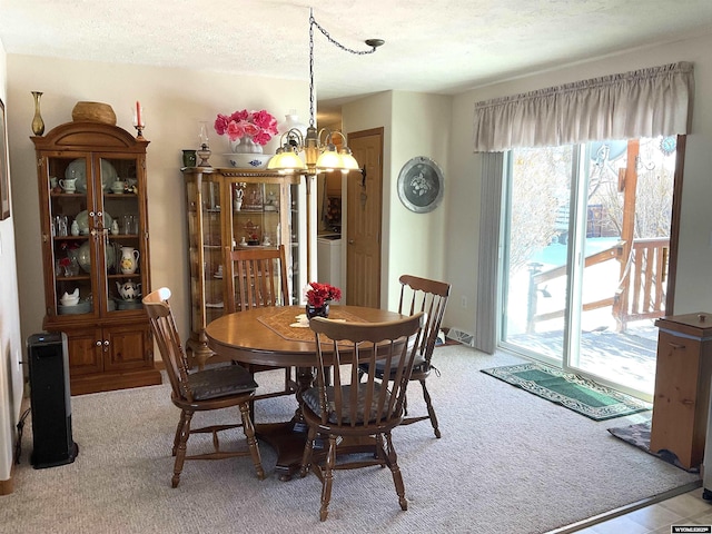 carpeted dining space featuring a notable chandelier and a textured ceiling