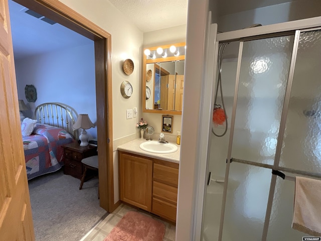 bathroom with vanity, a shower with door, and a textured ceiling