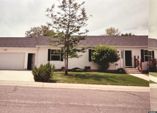 ranch-style house with a garage and a front lawn