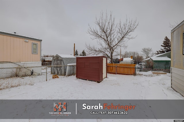 yard layered in snow with a storage shed