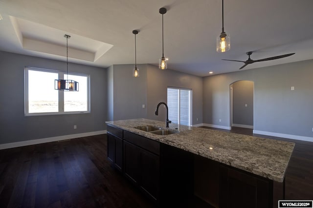 kitchen featuring pendant lighting, sink, a tray ceiling, and light stone countertops